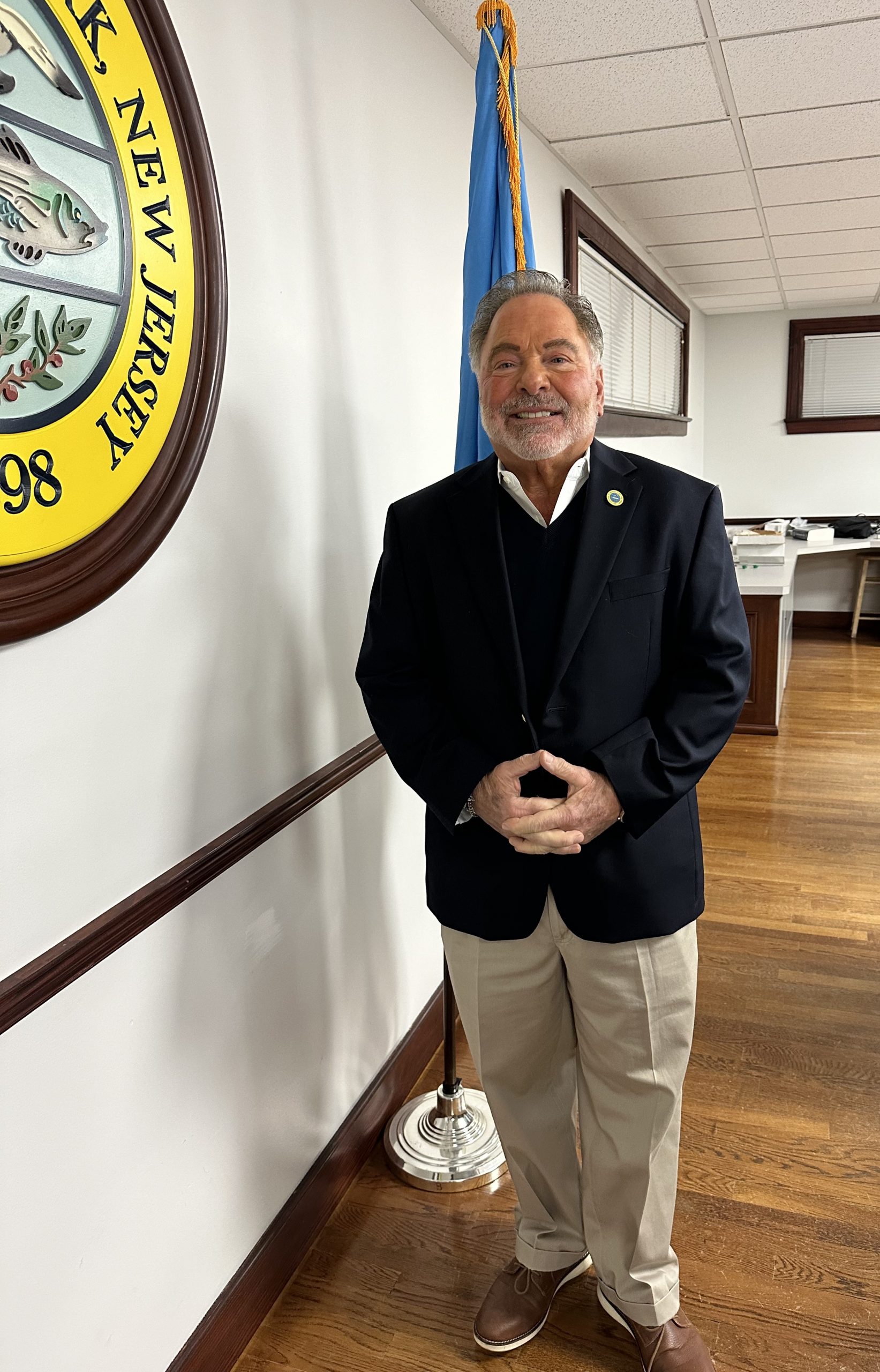Council Member Jerry Rotonda standing in front of the American Flag and the Borough Seal